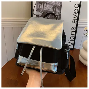 Handheld lifestyle shot of a modern black nylon backpack with metallic silver accents