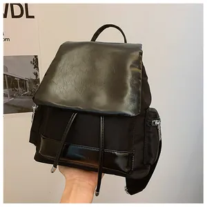 Detail of black backpack showing contrast textures of nylon and glossy wrinkled faux leather