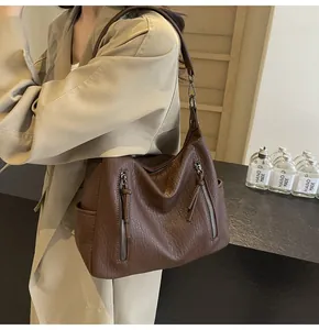 Detail of dark brown tote bag with lychee texture and vertical decorative zippers