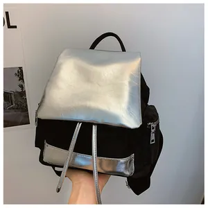 Detail of a large color-block backpack showing the silver metallic flap and drawstring