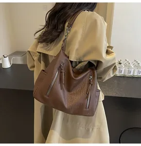 Detail of soft brown leather tote bag with silver zippers and stylish tassel accents