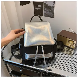 Detail of contrast backpack showing silver textured flap and black nylon side zipper pocket