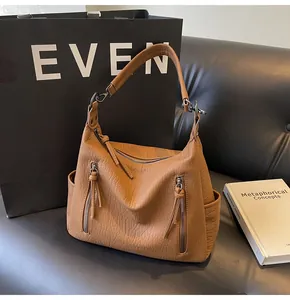 Detail of caramel lychee grain leather tote showing metal zippers and textured shoulder strap