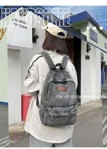 Détail du sac à dos en jean durable montrant la texture grise et le logo en cuir