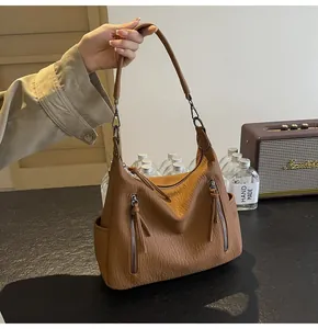 Detail of camel brown lychee texture tote bag with dual front zippers and tassels