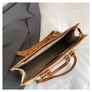 Detailed interior of the canvas tote bag showing the zipper pocket and brown leather handles