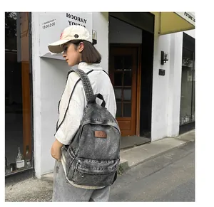 Vue détaillée du sac à dos en denim délavé avec poches latérales et étiquette en cuir