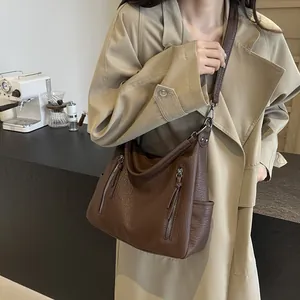 Retro dark brown tote bag with adjustable strap worn by a model in a modern cafe