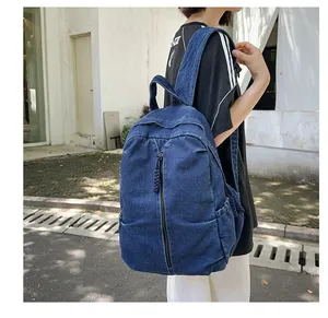 Détail d'un sac à dos en denim bleu délavé avec fermeture éclair verticale et poches