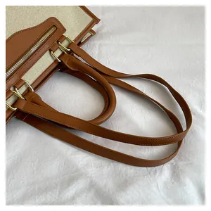 Close-up of canvas tote bag showing top zipper closure and brown faux leather handle detail
