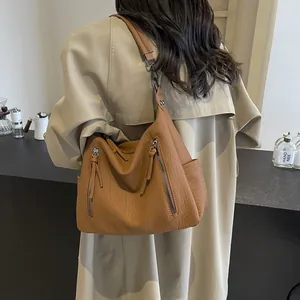Brown lychee leather hobo bag with dual vertical zippers for trendy urban commute