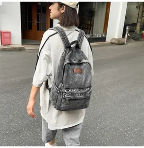 Détail d'un sac à dos vintage en denim avec écusson en cuir marron et poche avant zippée