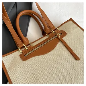 Detail of canvas tote bag with brown leather trim and metal zipper pocket