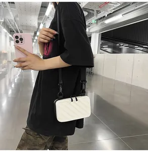 Close-up of white mini suitcase crossbody bag with textured stripes and black shoulder strap