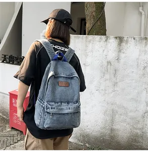 Détail d'un sac à dos en denim délavé bleu clair avec patch en cuir et bretelles