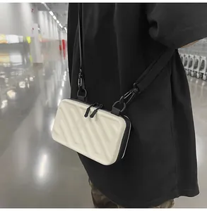 Detail of minimalist cream crossbody bag with black trim and striped hard shell texture