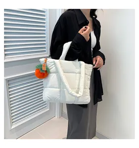 Detail der weißen gesteppten Nylon-Einkaufstasche mit einem süßen orangefarbenen Anhänger