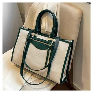 Close-up of canvas tote bag with dark green leather trim and golden metal hardware details