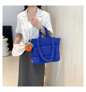 Detail der leuchtend blauen Stepptasche mit orangefarbenem Plüsch-Anhänger und Polsterung