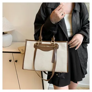 Lifestyle view of a large canvas tote bag with brown leather trim and metal zipper