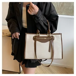 Close-up of contrast canvas tote bag with brown leather trim and tassel zipper pocket