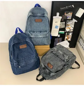 Trois sacs à dos en jean bleu clair, bleu foncé et noir avec fournitures scolaires