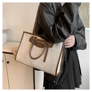 Detail of canvas tote bag with brown leather trim and front metal zipper pocket