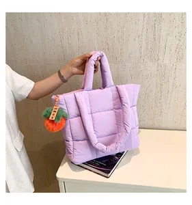 Detail der hellvioletten gesteppten Nylon-Tragetasche mit orangefarbenem Plüsch-Anhänger