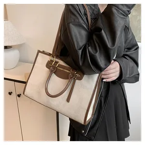 Contrast canvas tote bag detail featuring dual handles and brown leather trim on model