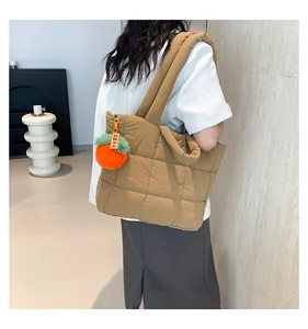 Detailansicht der khakifarbene Stepptasche mit dekorativem orangefarbenem Anhänger