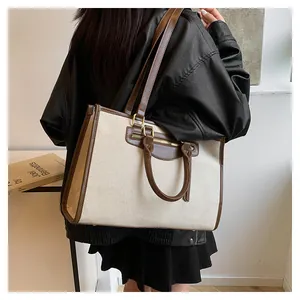 Detail of canvas tote bag with brown leather trim and front zipper pocket on model