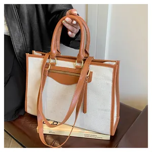 Detail of canvas and leather contrast tote bag showing zipper pocket and long handles
