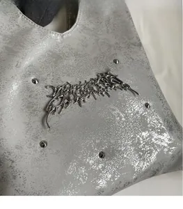 Primo piano della borsa in pelle argento con hardware gotico e dettagli di rivetti