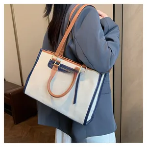 Detail of canvas tote with brown leather handles and blue contrast trim and zipper pocket