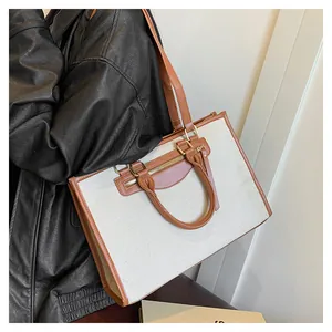Detailed close-up of large canvas tote bag featuring contrast leather trim and metal zipper