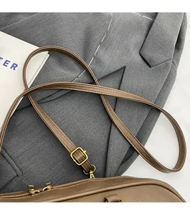 Detail of adjustable golden buckle and smooth long strap on a brown leather shoulder bag