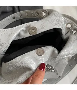 Dettaglio della borsa a tracolla argento metallizzato con chiusura magnetica e fodera nera