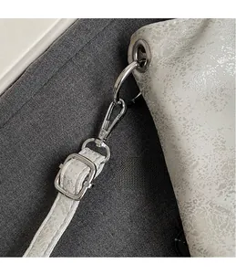Dettaglio macro del gancio in metallo argento e texture martellata della borsa a tracolla