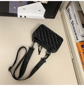 Detailed view of black hardshell crossbody bag with striped texture and wide nylon strap
