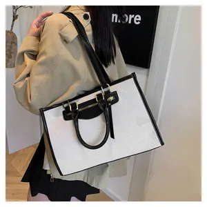 Detail view of large canvas tote bag with black leather trim and gold hardware accents