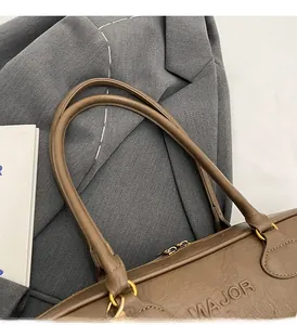 Detail of brown leather handbag with embossed MAJOR letters and golden metal rings