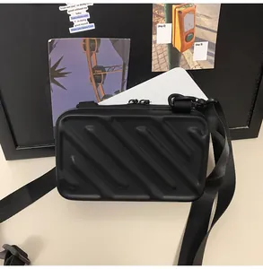 Close-up of black hardshell crossbody bag featuring diagonal textured stripes and dual zippers