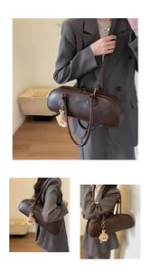Detail showing deep brown cylinder shoulder bag with logo embossing and a plush charm