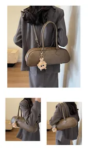 Detail view of brown faux leather baguette bag with logo embossing and plush charm