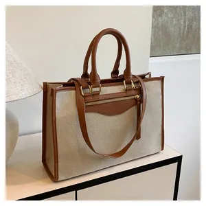 Detail of canvas tote bag with brown leather trim and high-quality gold metal hardware