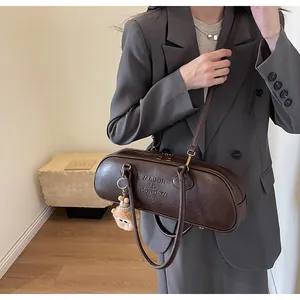 Detail of dark brown Boston barrel bag with brand logo and cute bear charm on model