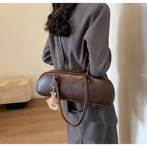 Detail of dark brown leather baguette bag featuring embossed logo and plush toy charm