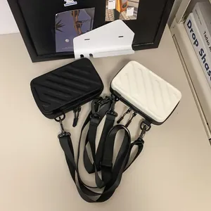 Mini suitcase-style crossbody bags in black and white with textured vertical stripes