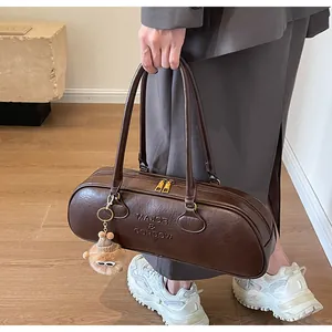 Retro brown cylinder bag detail with embossed lettering and plush bear charm