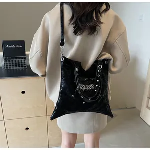 Dettaglio della borsa tote in pelle verniciata nera con occhielli e ciondoli gothic